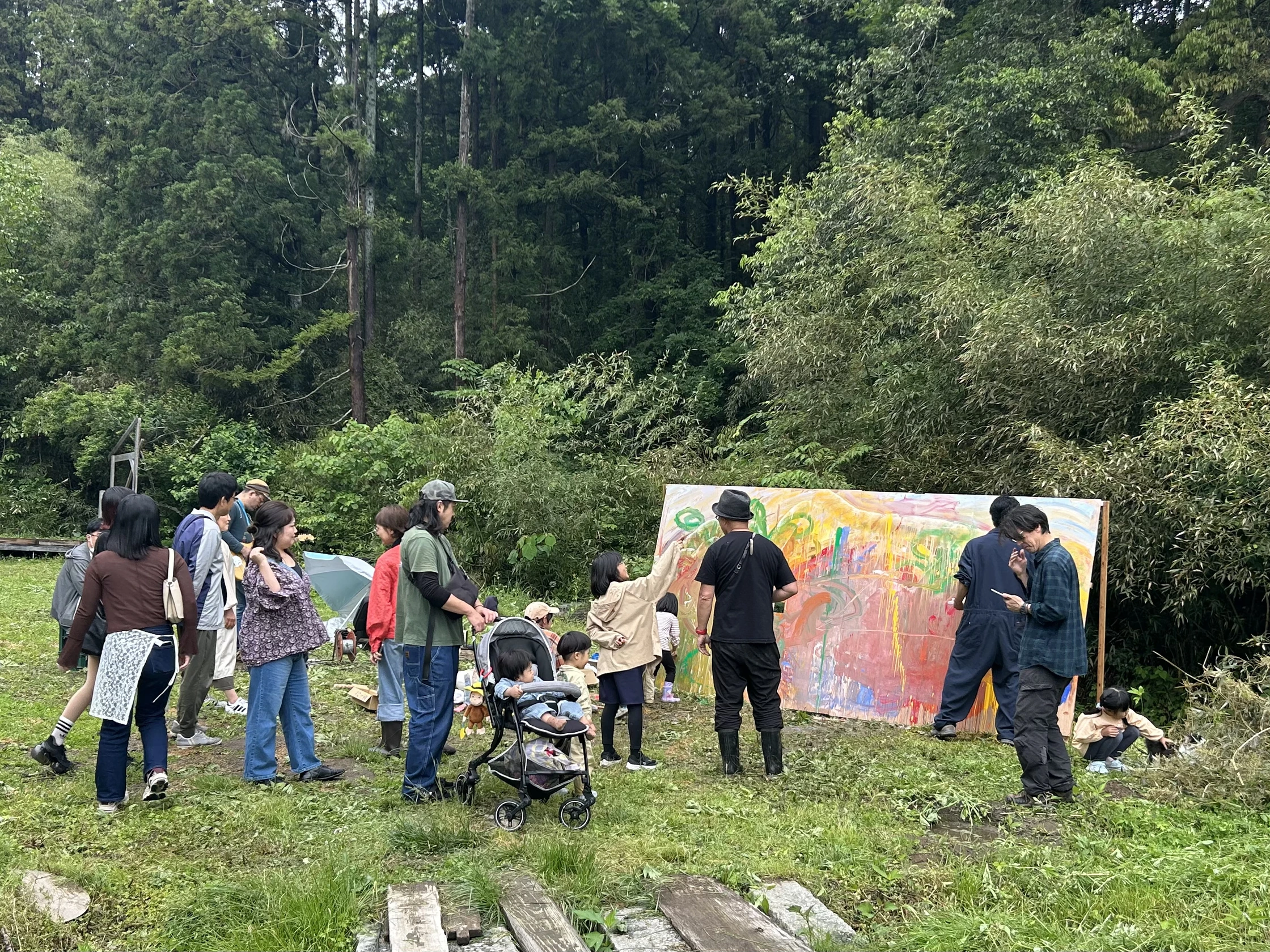 森の前で大きな絵を囲む人々